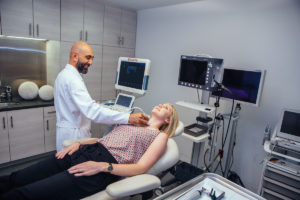 Doctor performing an ultrasound examination on a patient's neck in a medical office.