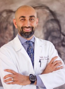 Doctor in a white coat smiling with arms crossed.