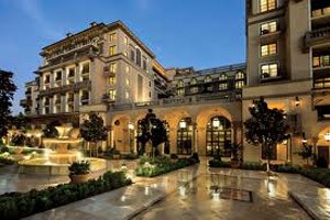 Luxury hotel facade at dusk with illuminated entrance and courtyard.