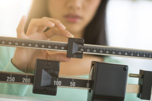 Person adjusting a balance scale during a weight measurement process.