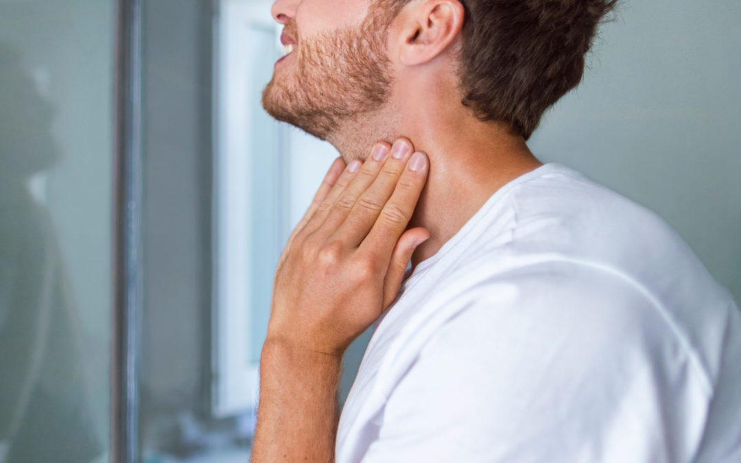 Man touching his throat in a gesture that suggests he's checking his neck or thyroid area.