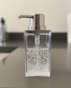 Hand sanitizer in a clear dispenser on a table