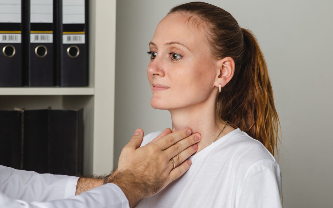 Doctor examining a patient's thyroid gland in a clinical setting.