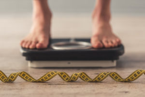 feet on a scale with measuring tape in front of it